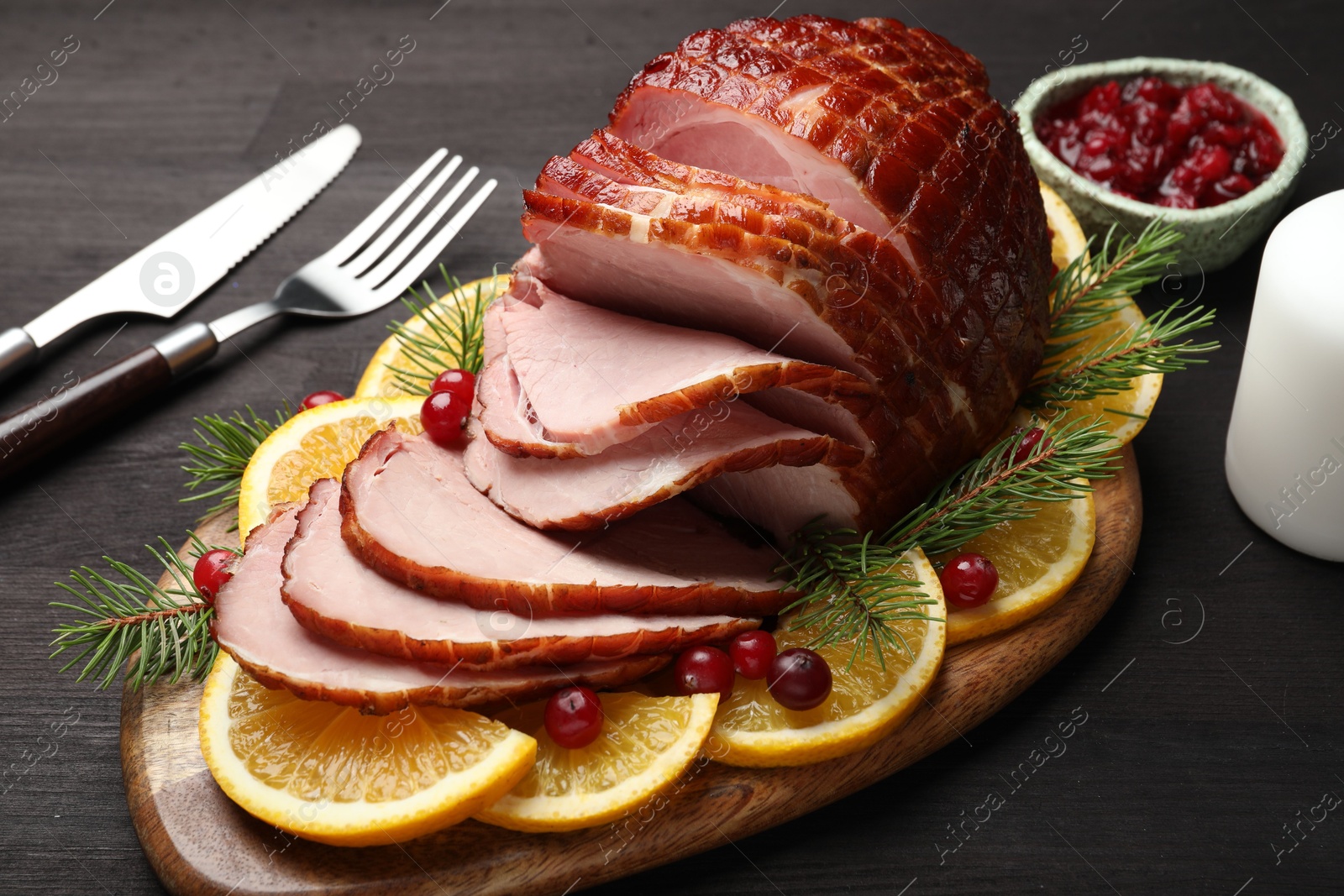 Photo of Tasty baked ham served on black wooden table