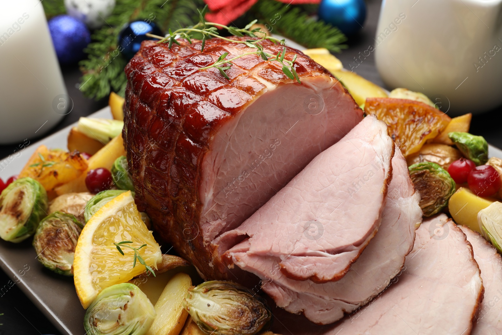 Photo of Tasty baked ham served with vegetables and oranges on table, closeup