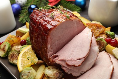 Tasty baked ham served with vegetables and oranges on table, closeup