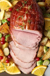 Tasty baked ham served with oranges and vegetables on tray, top view