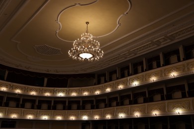 Photo of Stylish vintage chandelier in theatre, low angle view