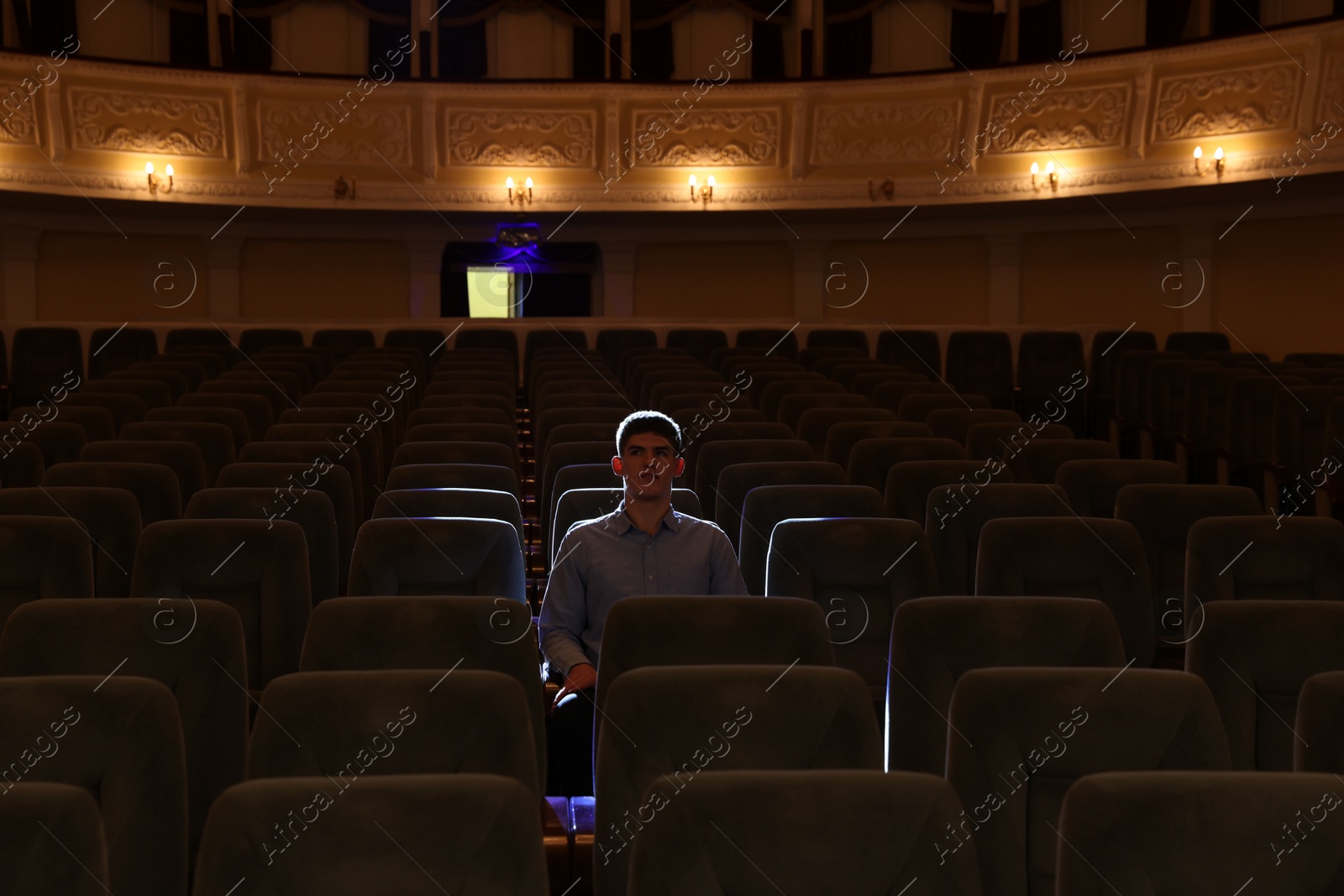 Photo of Young man watching theatrical performance in theatre