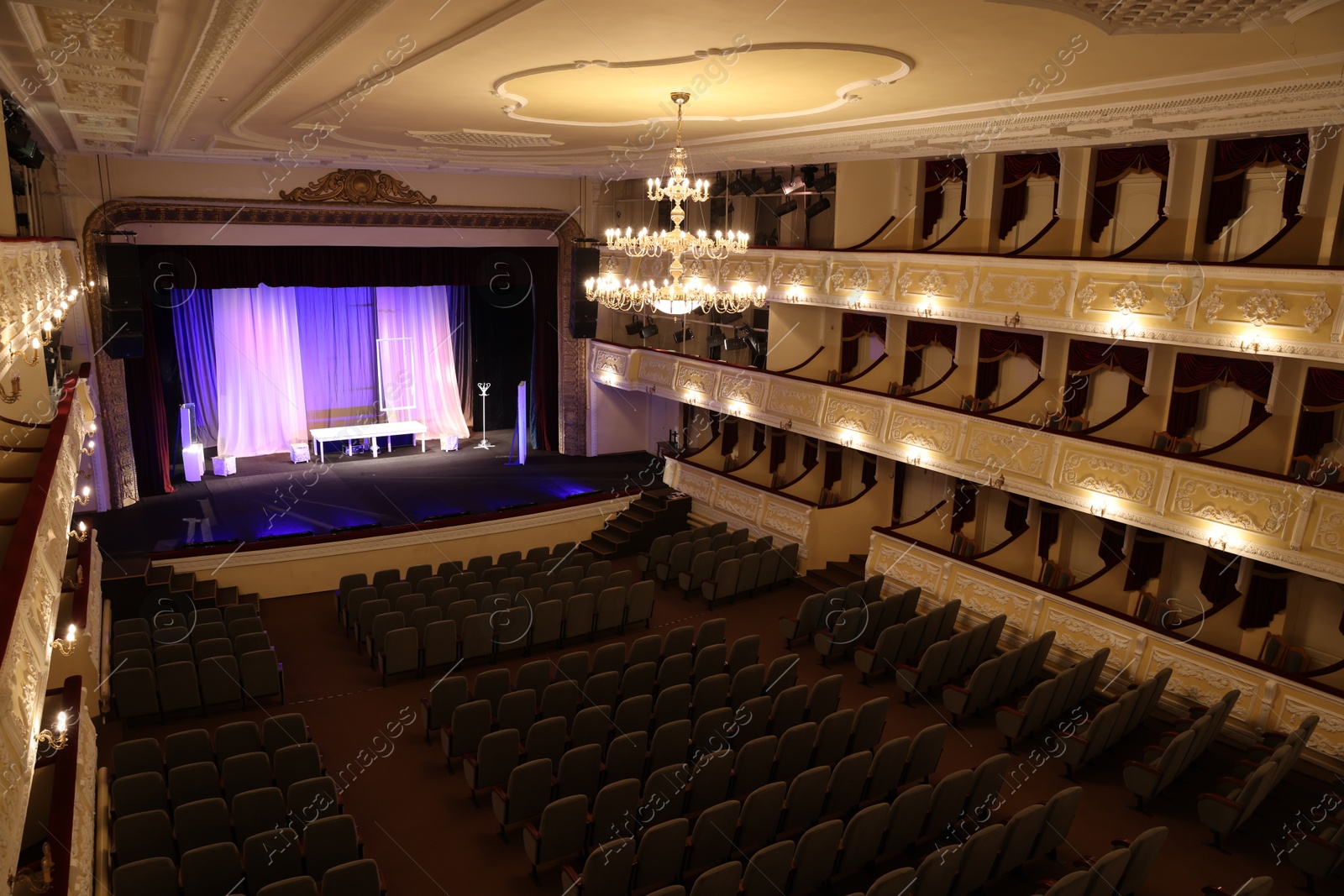 Photo of Theatre interior with stage, rows of comfortable seats and beautiful chandelier