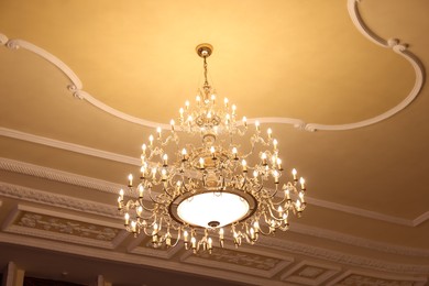 Photo of Stylish vintage chandelier in theatre, low angle view