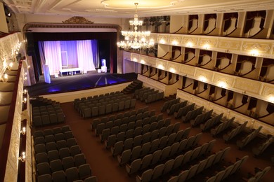 Photo of Theatre interior with stage, rows of comfortable seats and beautiful chandelier