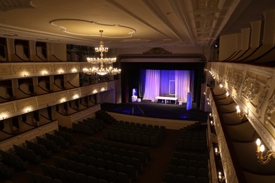 Photo of Theatre interior with stage, rows of comfortable seats and beautiful chandelier