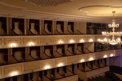 Photo of Balconies with comfortable chairs and beautiful chandelier in theatre