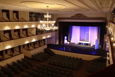 Photo of Theatre interior with stage, rows of comfortable seats and beautiful chandelier