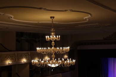 Photo of Stylish vintage chandelier on ceiling in theatre