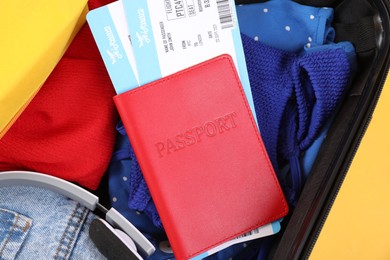 Photo of Travel abroad. Packed suitcase, passport and tickets on yellow background, closeup