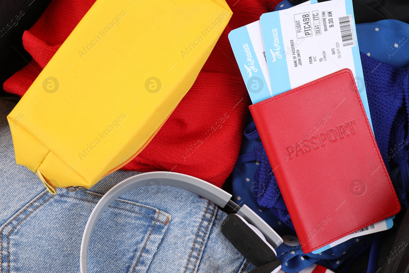 Photo of Different clothes, headphones and passport with tickets, closeup. Travel luggage