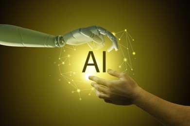 Image of AI abbreviation between human hand and robot arm on black background