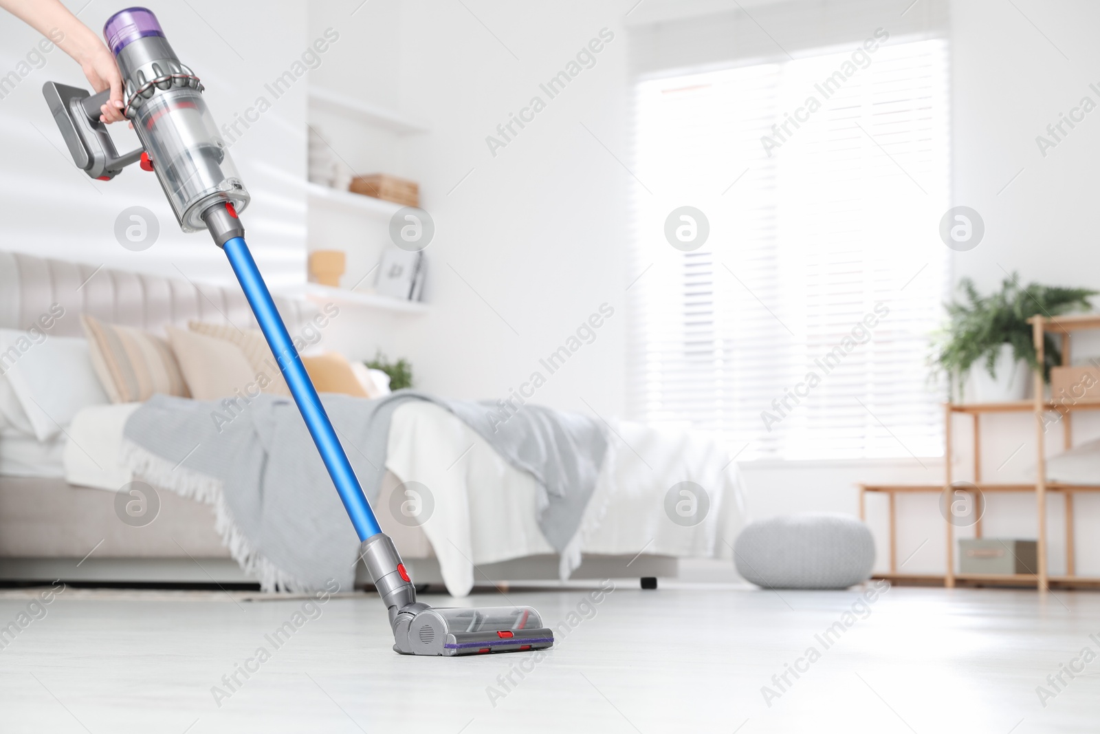 Photo of Woman cleaning floor with cordless vacuum cleaner indoors, closeup. Space for text