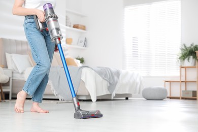 Photo of Woman cleaning floor with cordless vacuum cleaner indoors, closeup. Space for text