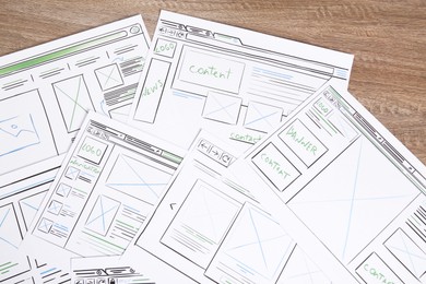 Photo of Developing UI design. Sketches of website wireframes on wooden table, top view