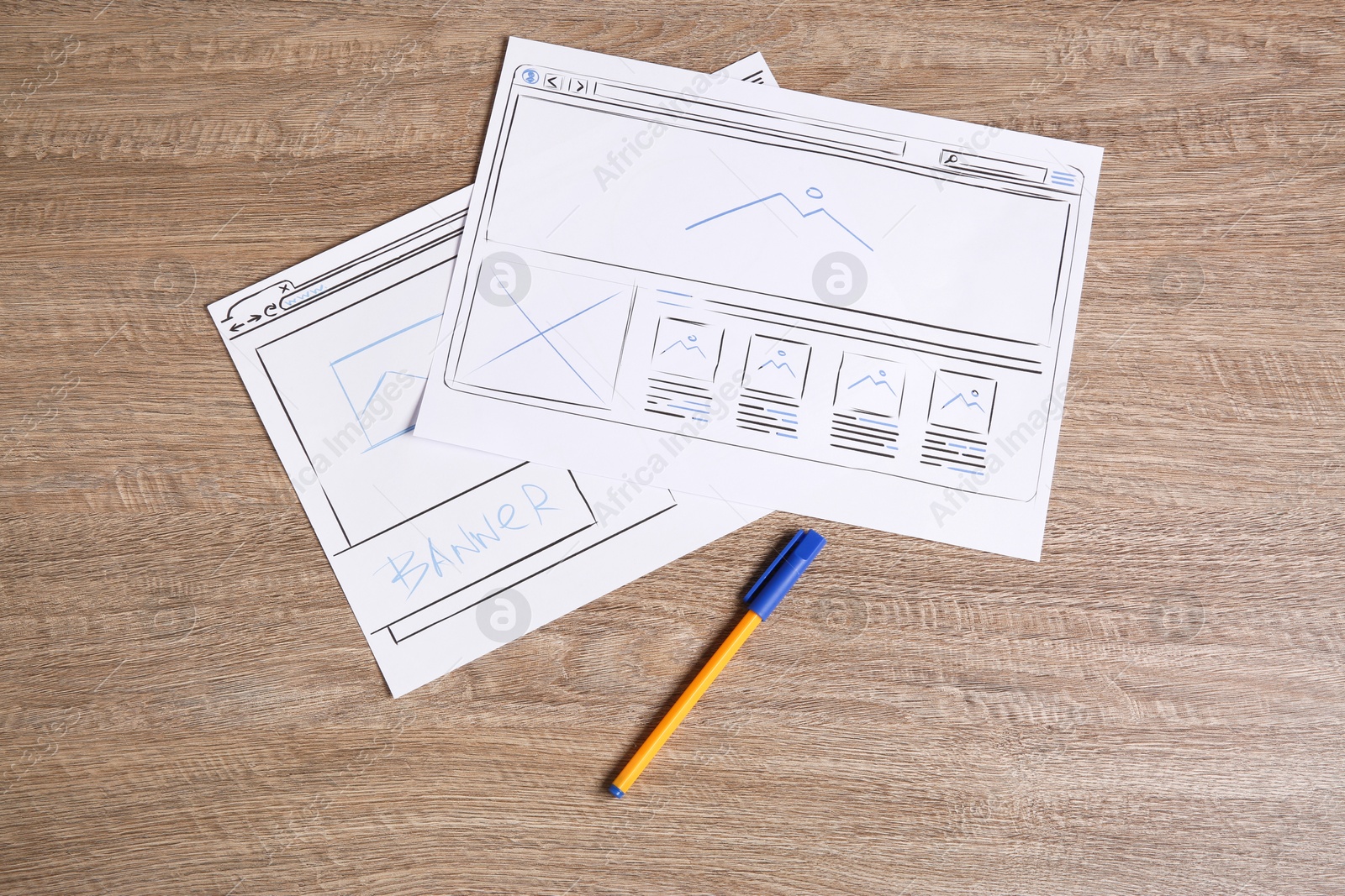 Photo of Developing UI design. Sketches of website wireframes and pen on wooden table, top view