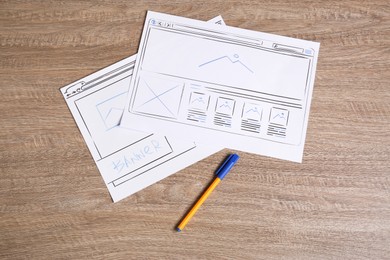 Developing UI design. Sketches of website wireframes and pen on wooden table, top view