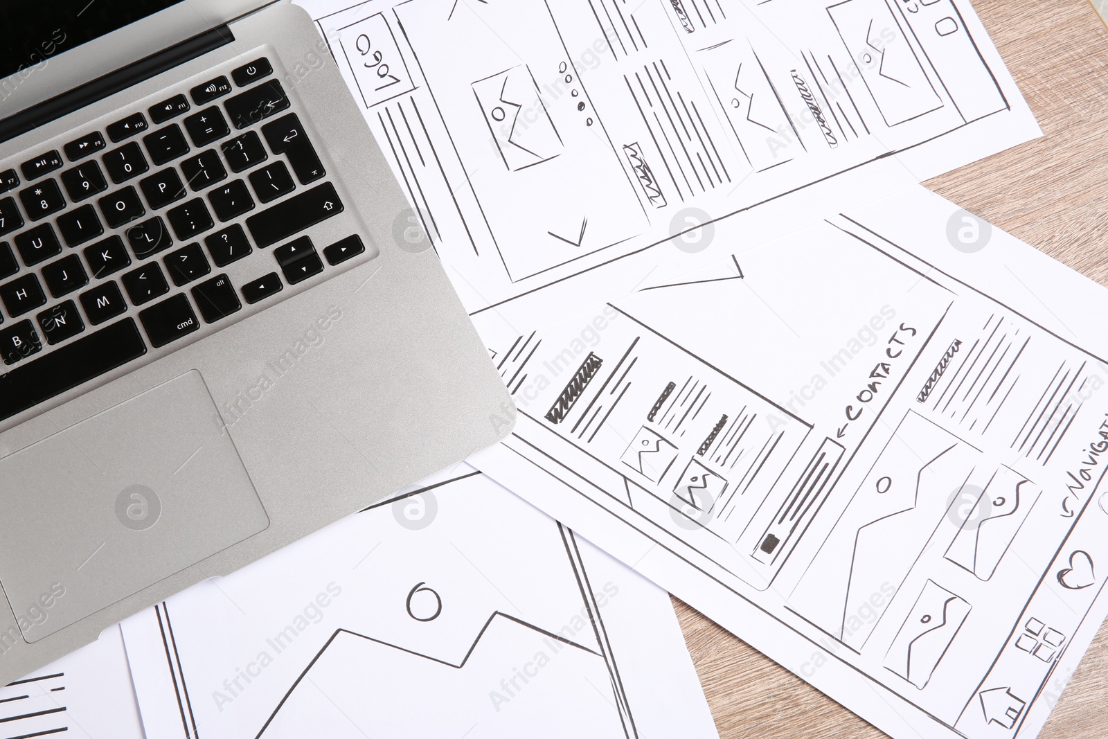 Photo of Developing UI design. Sketches of website wireframes and laptop on wooden table, top view