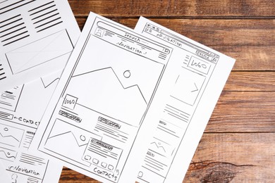 Photo of Developing UI design. Sketches of website wireframes on wooden table, top view