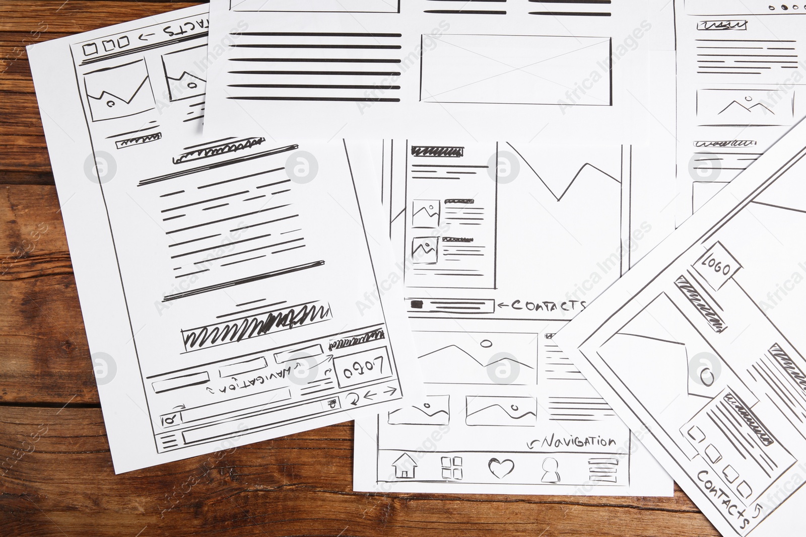 Photo of Developing UI design. Sketches of website wireframes on wooden table, top view