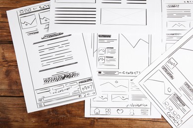 Developing UI design. Sketches of website wireframes on wooden table, top view