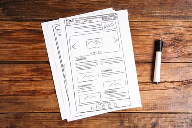 Developing UI design. Sketches of website wireframes and felt pen on wooden table, top view