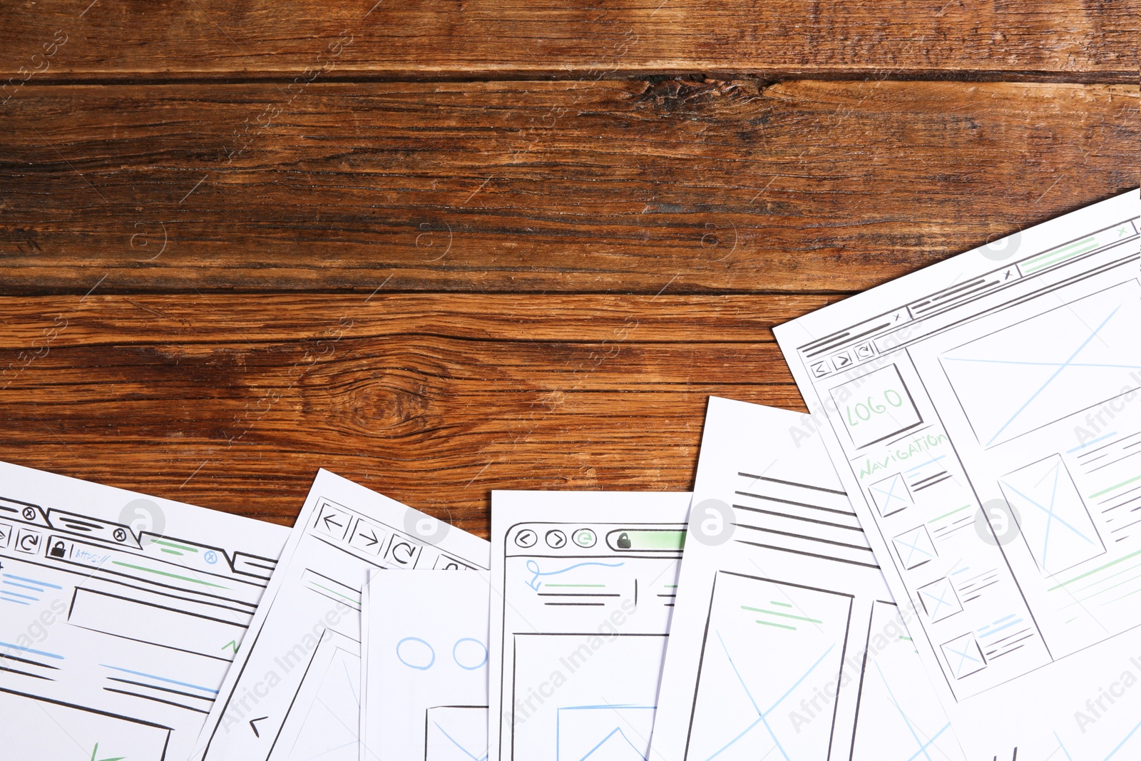 Photo of Developing UI design. Sketches of website wireframes on wooden table, top view