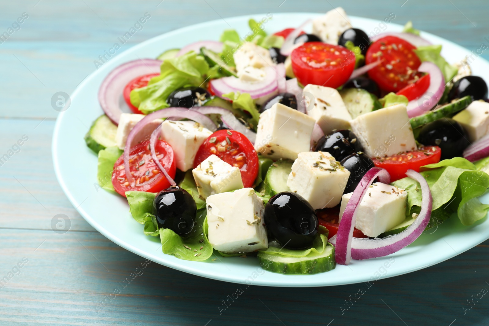 Photo of Delicious salad with feta cheese on blue wooden table, closeup