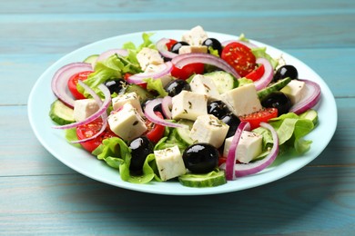 Photo of Delicious salad with feta cheese on blue wooden table, closeup