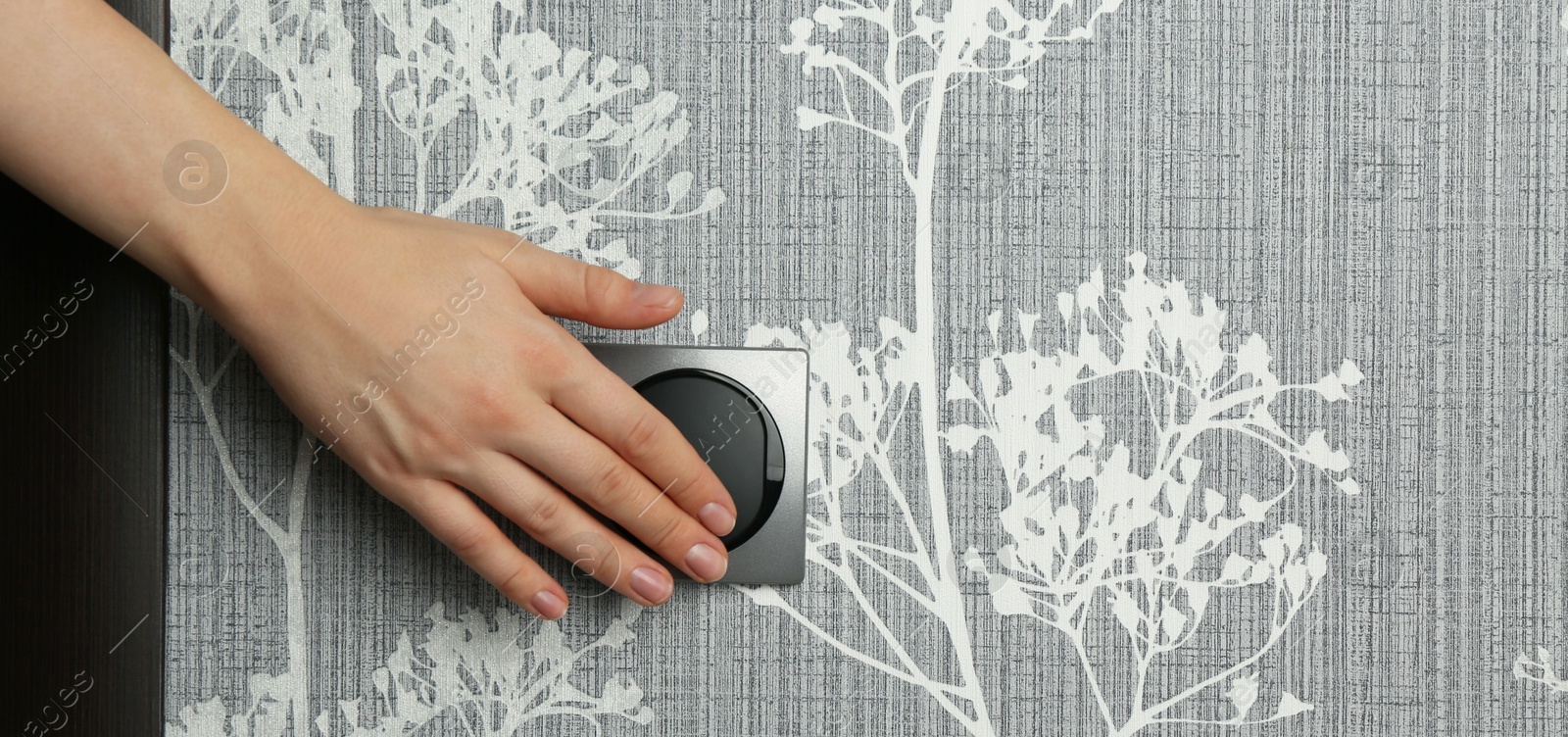 Photo of Woman turning light switch on, closeup view