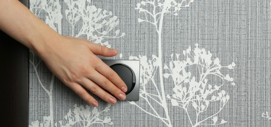 Photo of Woman turning light switch on, closeup view