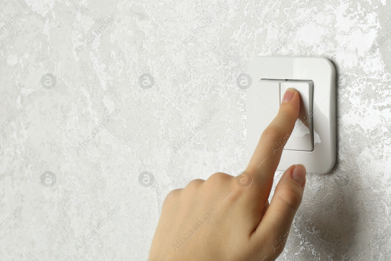 Photo of Woman turning light switch on, closeup view