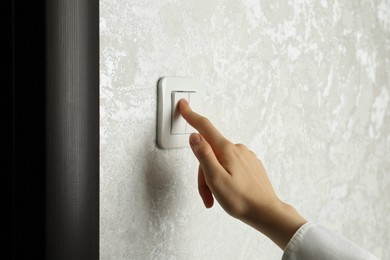 Photo of Woman turning light switch on, closeup view