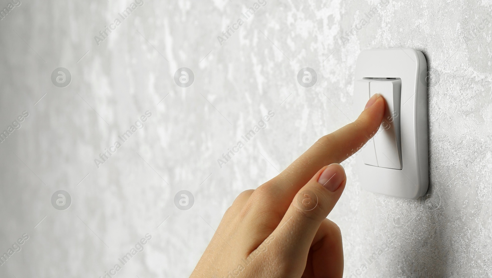 Photo of Woman turning light switch on, closeup view