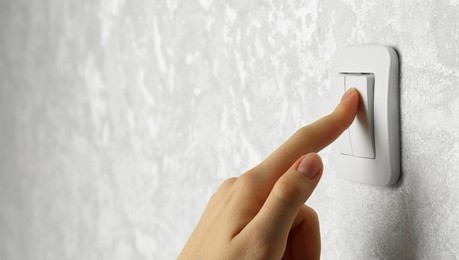 Photo of Woman turning light switch on, closeup view