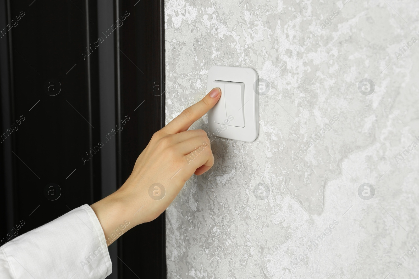 Photo of Woman turning light switch on, closeup view