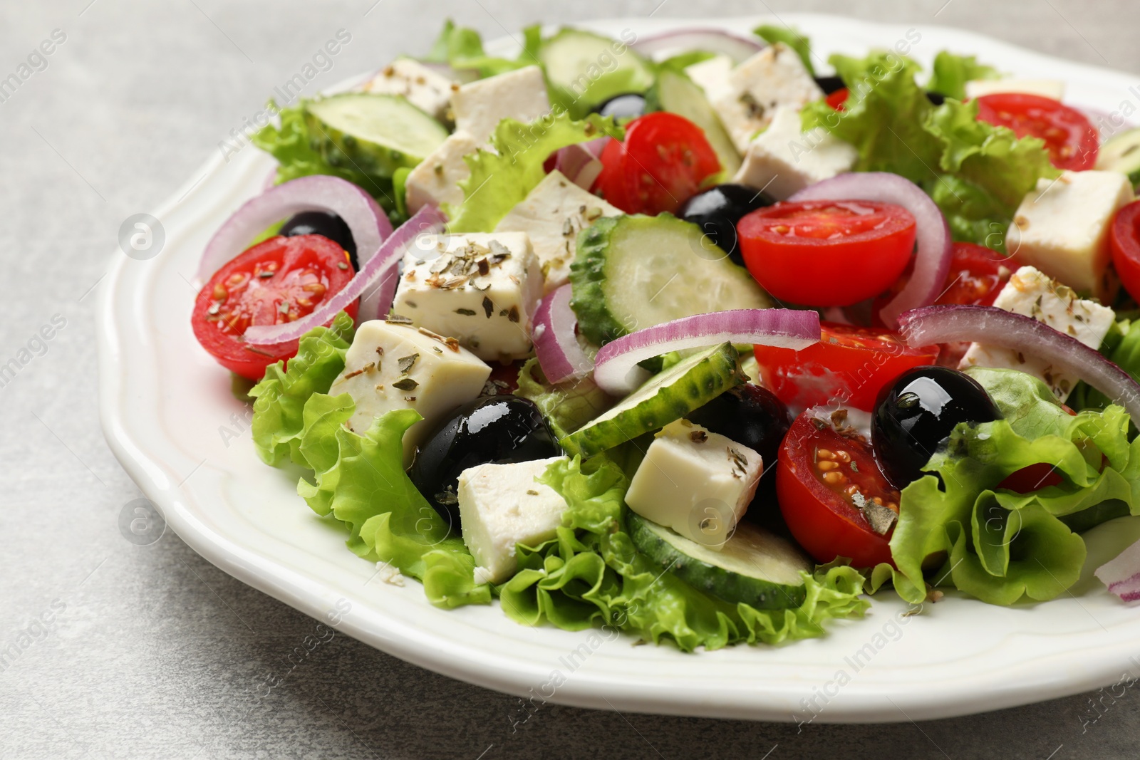 Photo of Delicious salad with feta cheese on gray textured table, closeup