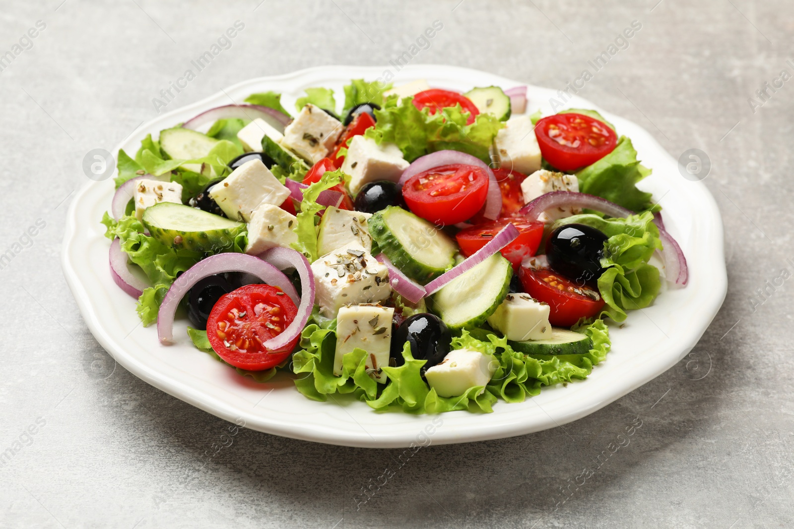 Photo of Delicious salad with feta cheese on gray textured table, closeup