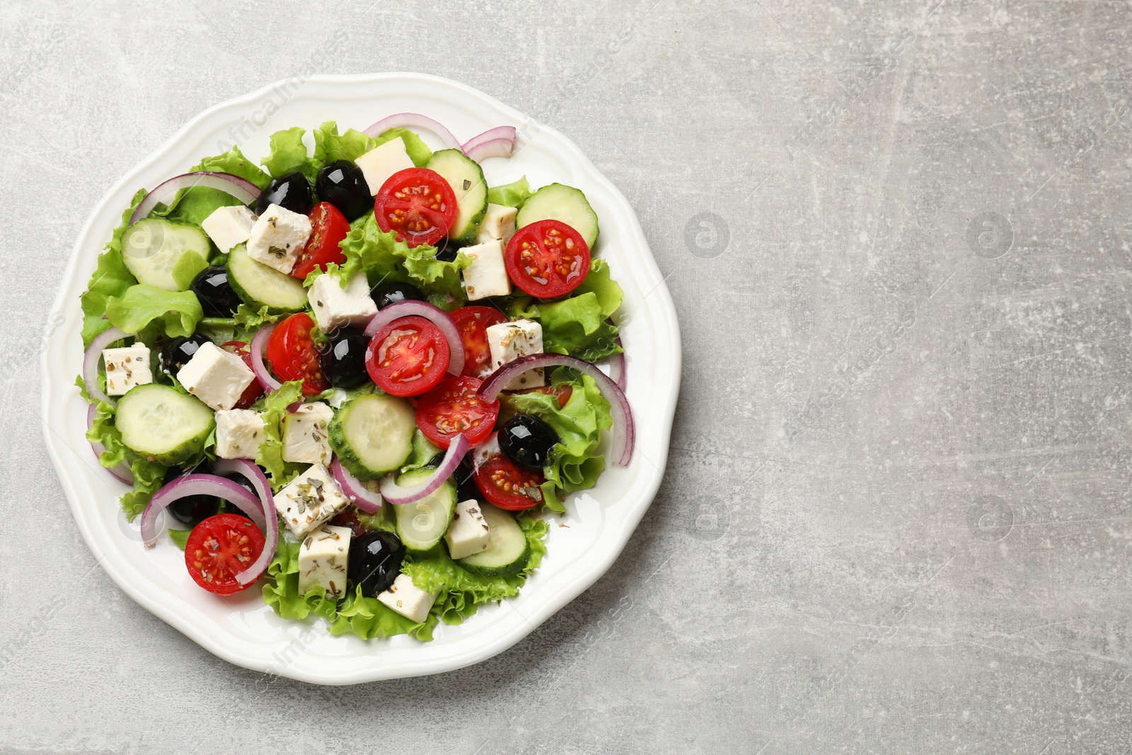 Photo of Delicious salad with feta cheese on gray textured table, top view. Space for text