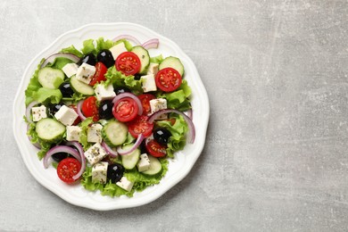 Photo of Delicious salad with feta cheese on gray textured table, top view. Space for text