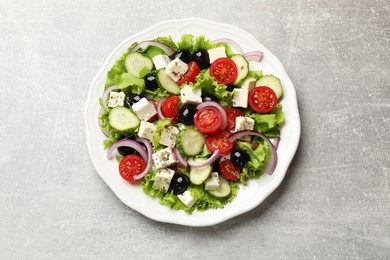 Photo of Delicious salad with feta cheese on gray textured table, top view