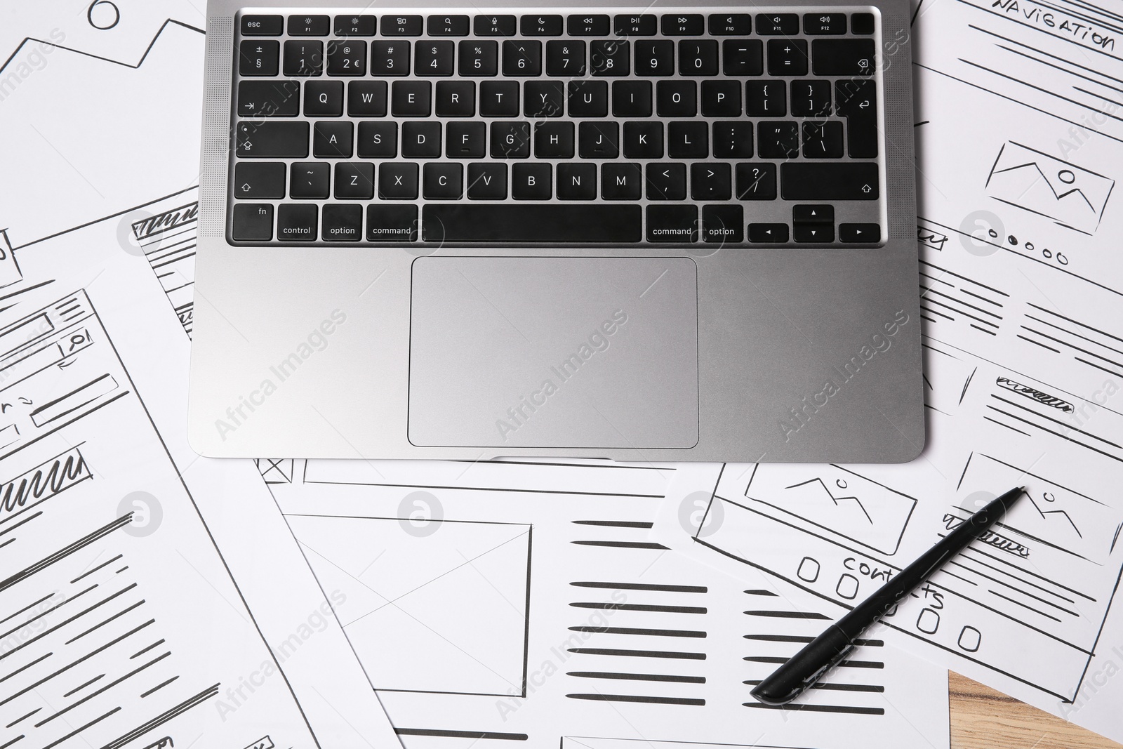 Photo of Website development. Sketches of wireframes, pen and laptop on wooden table, flat lay