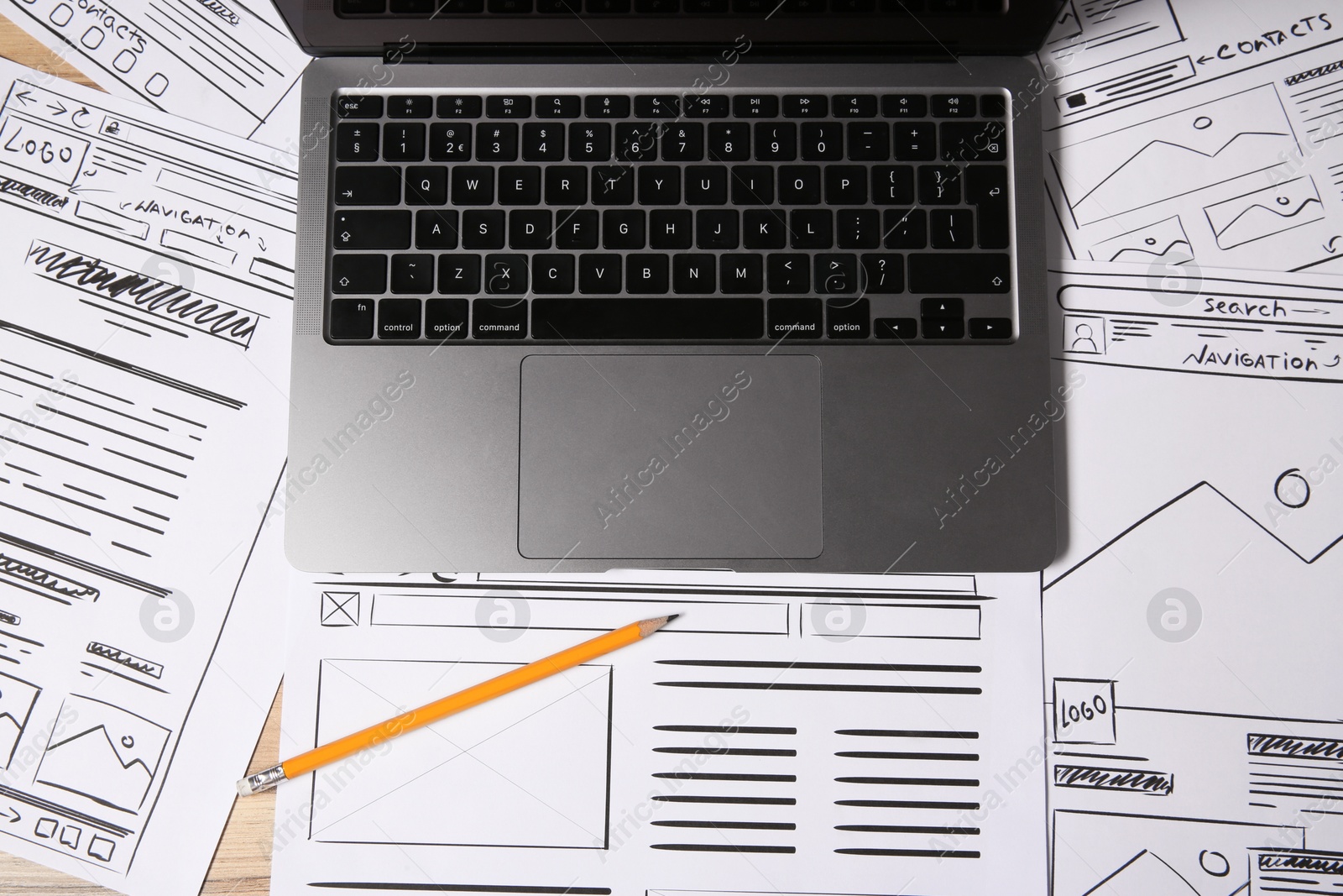 Photo of Website development. Sketches of wireframes, laptop and pencil on wooden table, flat lay