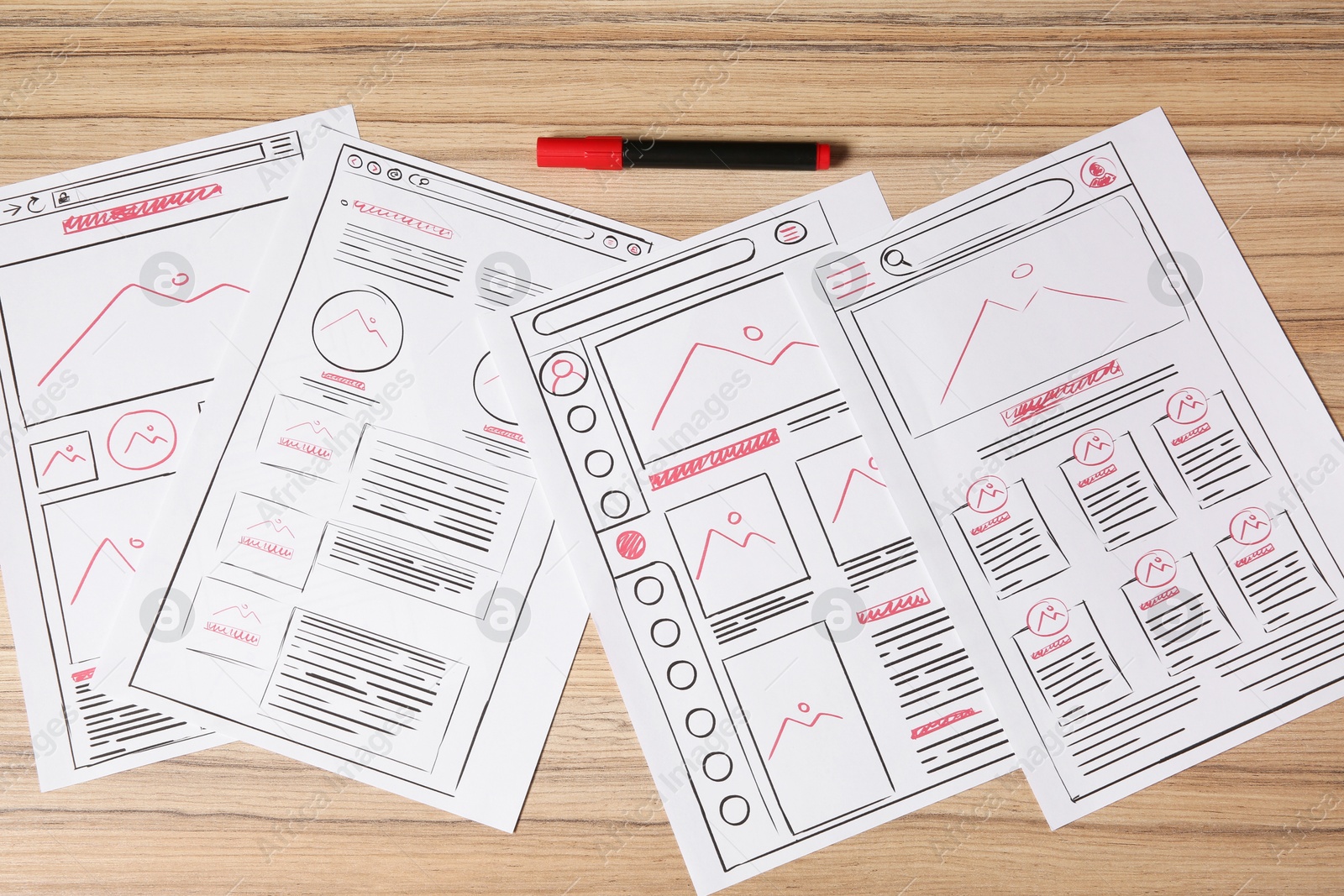 Photo of Website development. Sketches of wireframes and felt pen on wooden table, flat lay