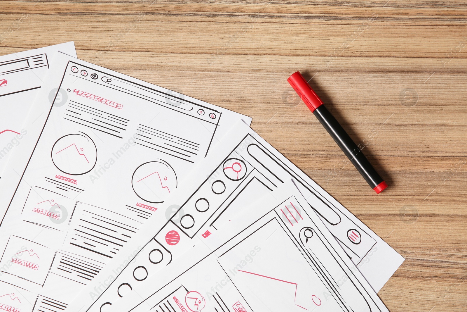 Photo of Website development. Sketches of wireframes and felt pen on wooden table, flat lay