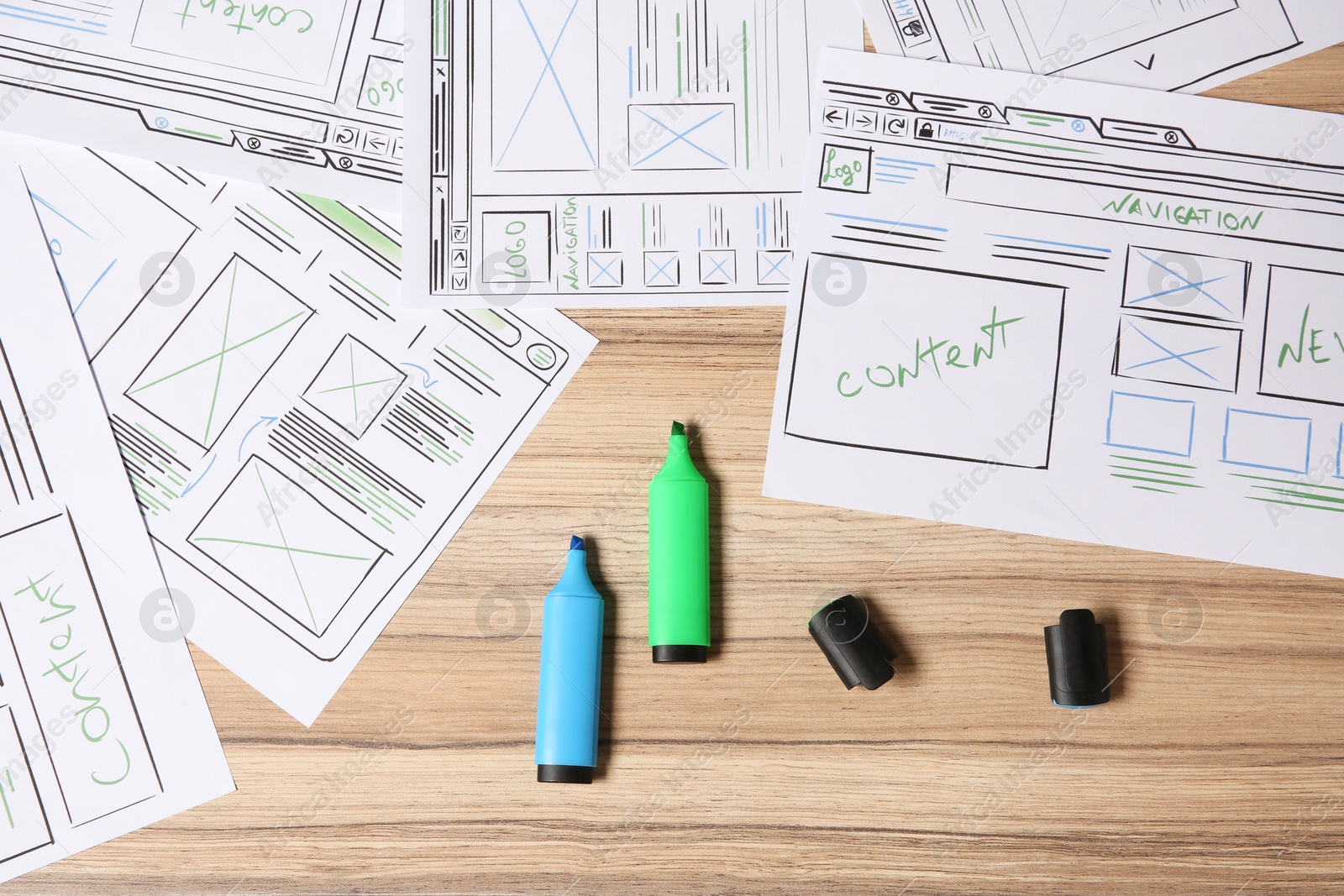 Photo of Website development. Sketches of wireframes and highlighters on wooden table, flat lay