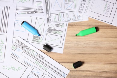 Photo of Website development. Sketches of wireframes and highlighters on wooden table, flat lay