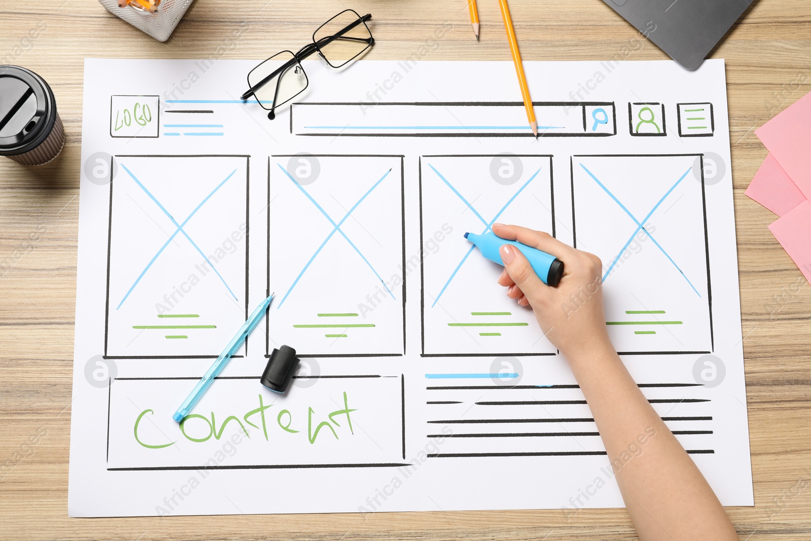 Photo of Website designer creating wireframe on paper with highlighter at wooden table, top view