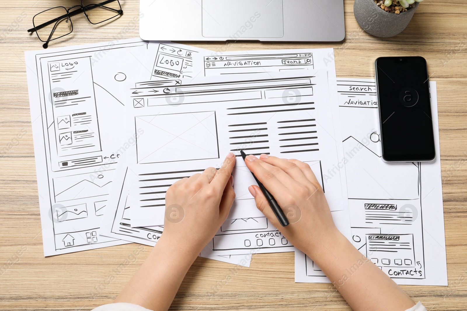 Photo of Website designer creating wireframe on paper with pen at wooden table, top view