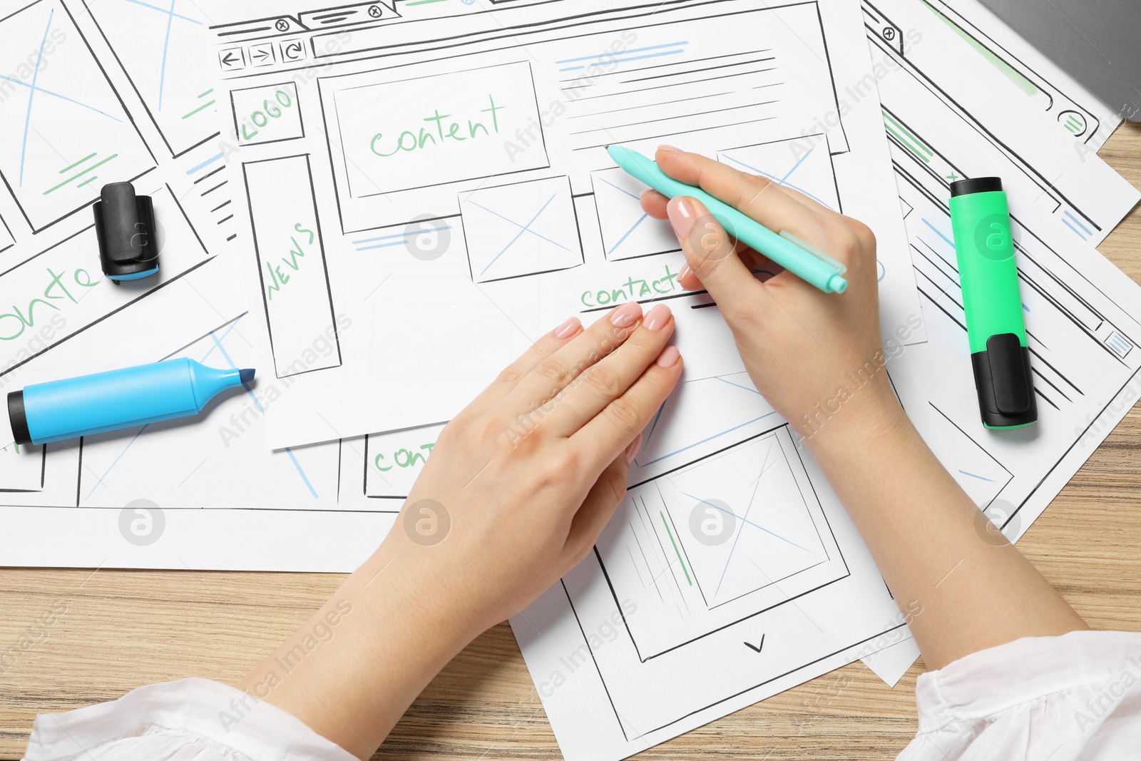 Photo of Website designer creating wireframe on paper with pen at wooden table, top view